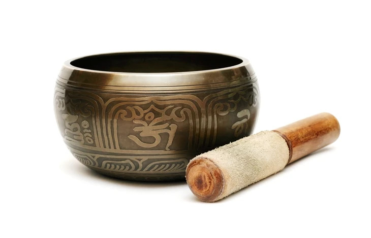Scène intérieure sur fond blanc présentant des objets de méditation et bien-être disposés pour une séance de relaxation ou thérapie sonore