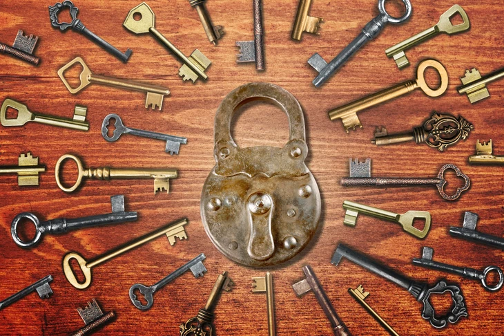 Scène d'atelier de serrurier avec cadenas ancien en laiton au centre, entouré de clés vintage disposées en cercle sur établi en bois