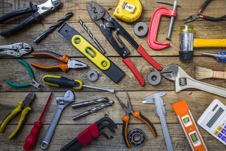 Atelier d'artisan avec outils de précision disposés sur établi en bois brut