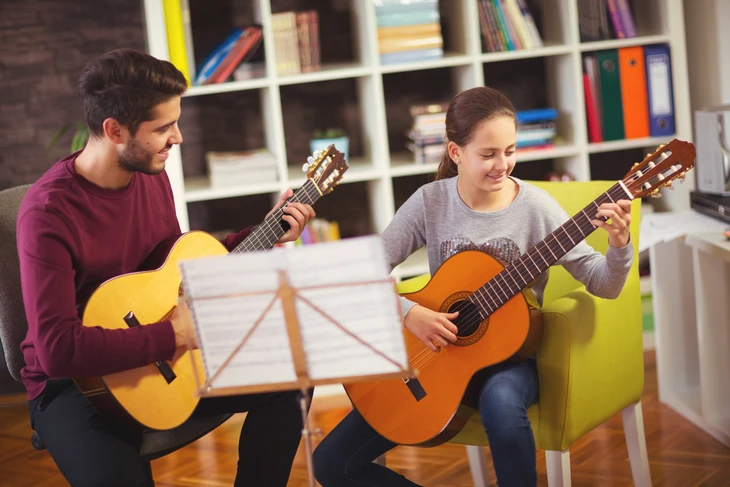 Séance de cours de guitare en duo dans un intérieur moderne avec bibliothèque