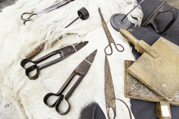 Atelier d'artisan traditionnel avec outils anciens disposés sur fourrure blanche et surface sombre