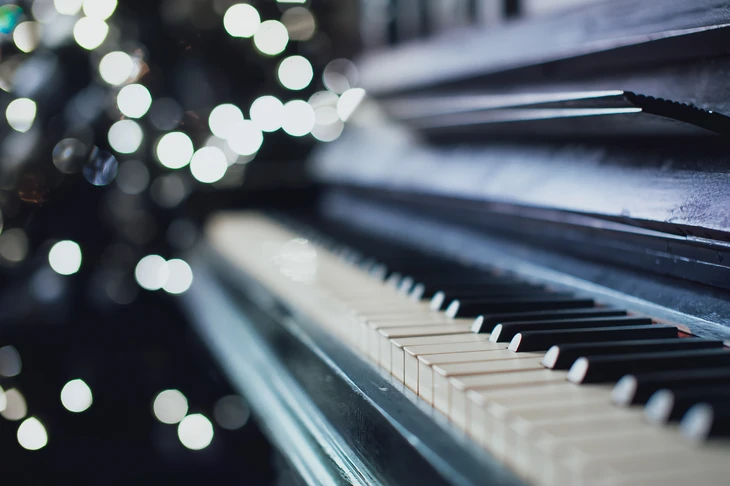 Scène intérieure avec piano à queue noir en gros plan, touches blanches et noires nettes au premier plan